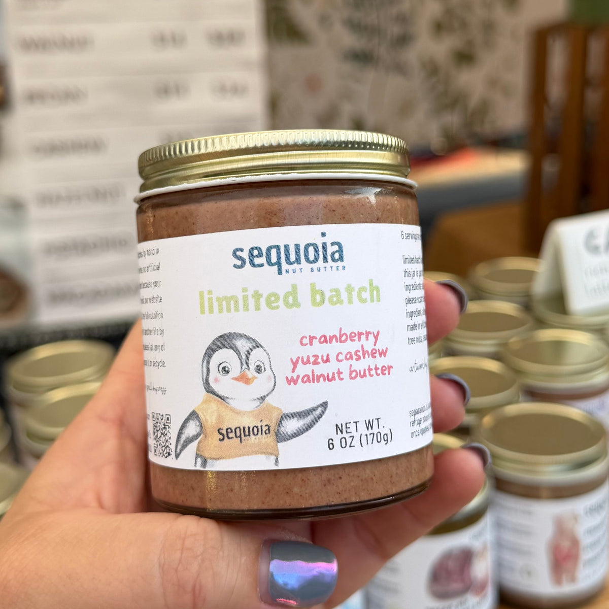 hand holding jar of cranberry yuzu cashew walnut butter made by sequoia nut butter